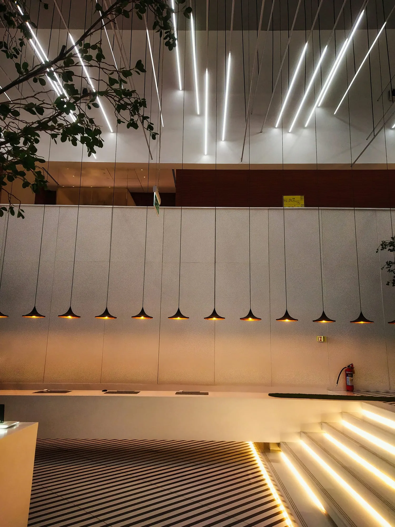 Heller Raum mit Lichtlinien an der Decke und Leuchten über einer Theke