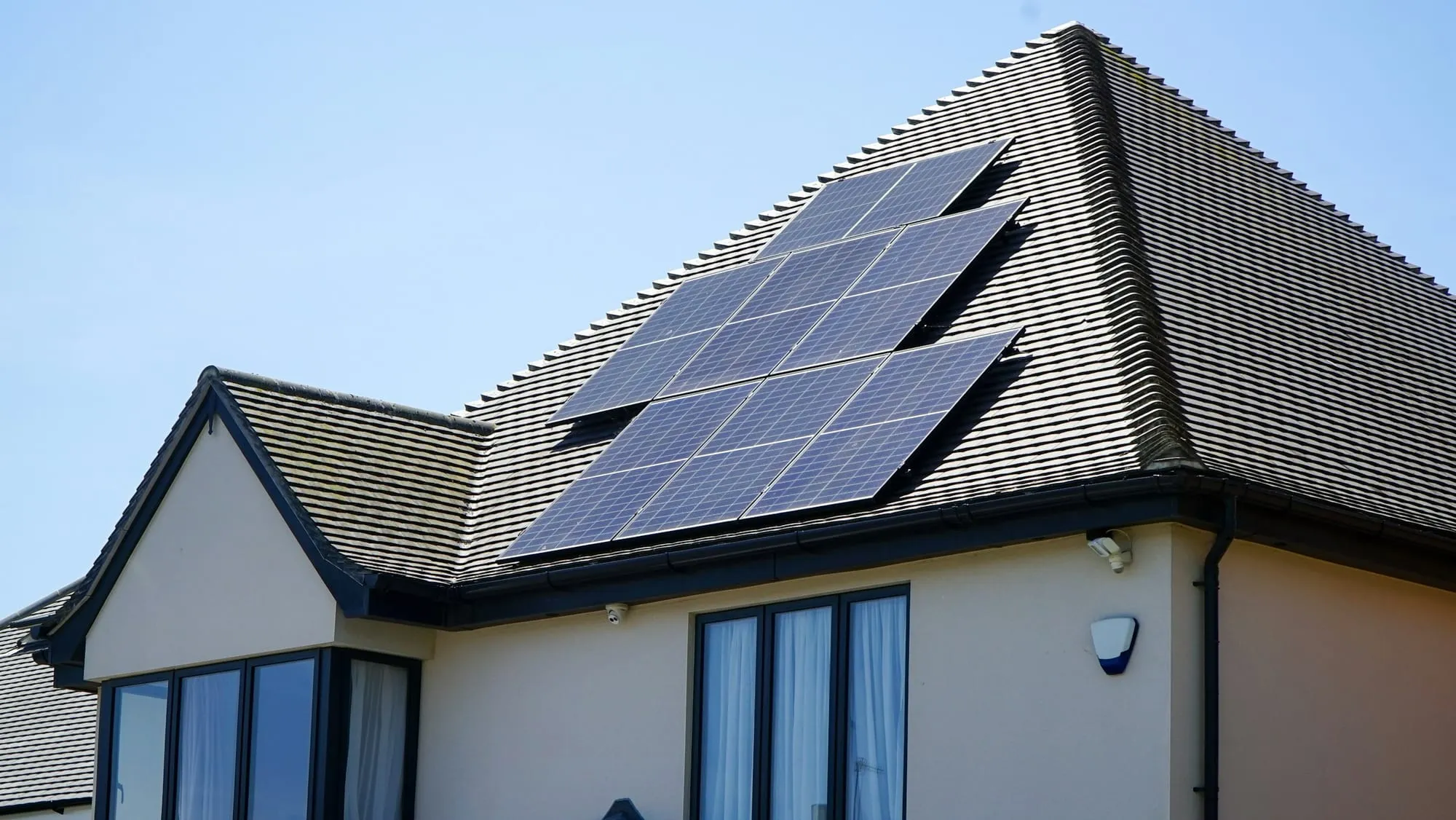 Wohnhaus mit Solarmodulen auf dem Dach vor blauem Himmel